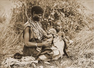 African woman with two small child seats in the grass