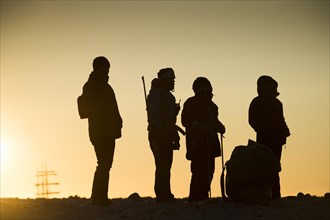 Tourists and tourist guides with rifle in backlight