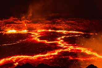 Glowing lava lake with eruptions at night