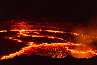 Glowing lava lake with eruptions at night