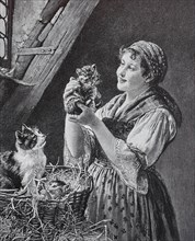 The domestic cat in a straw basket gave birth and the farmer's wife looks at the kittens