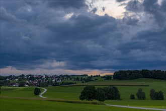 Thunderstorm sky with small village and meadows landscape