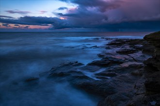 Rocky coast with dramatic dark clouds at sunset