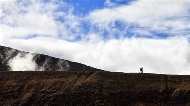 Two hikers at the crater rim as silhouettes