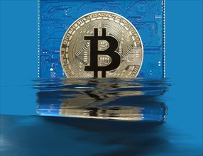 Bitcoin on a blue circuit board sinks into water