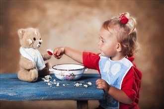 Four-year old girl feeding teddy bear