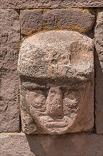 Stone head in wall of Kalasasaya Temple (place of standing stones) with monoliths from the pre-Inca period