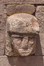 Stone head in wall of Kalasasaya Temple (place of standing stones) with monoliths from the pre-Inca period