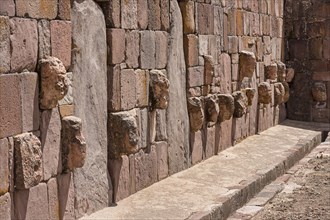 Stone heads in wall of Kalasasaya temple (place of standing stones) with monoliths from pre-Inca period