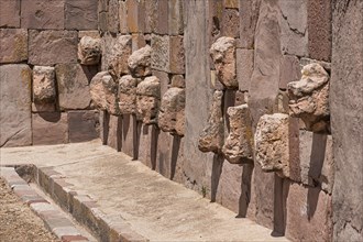 Stone heads in wall of Kalasasaya temple (place of standing stones) with monoliths from pre-Inca period