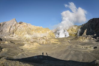 Fumarole on the volcanic island White Island with shadow of two people