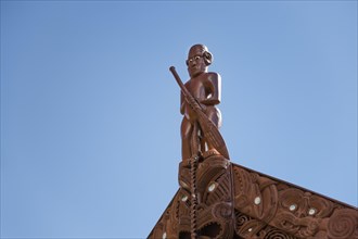 Traditional carving of a Maori statue on the roof of the assembly hall Te Whare Runanga