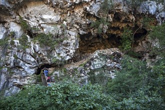 Tourists climbing into a cave in a karst cone called mogote