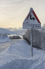 Wintry road with warning sign