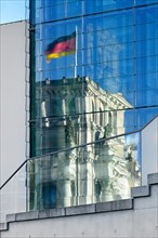 German flag on the Reichstag reflected in the glass facade of the Marie-Elisabeth-Luders-Haus