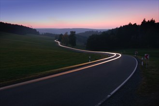 Car driving on winding country road in the evening