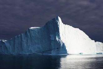 Iceberg under dark cloud sky