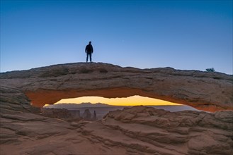 Young man standing on rock arch