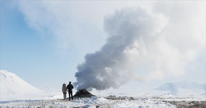 Two tourists standing beside steaming fumarole