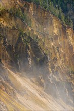 Rugged rock face of the Grand Canyon of the Yellowstone with water vapor of the waterfall