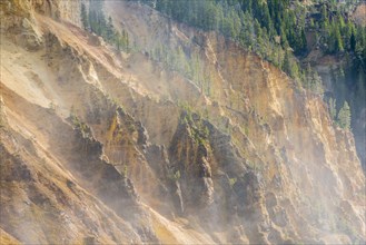 Rugged rock face of the Grand Canyon of the Yellowstone with water vapor of the waterfall