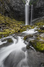 Waterfall flows over rocky outcrop