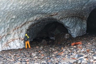 Man at the entrance of an ice cave of a glacier
