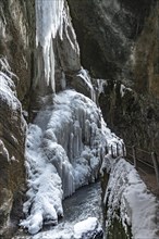 Path to Partnach wild river in the Partnach gorge with long icicles and snow in winter