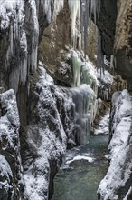 Wild river Partnach in the Partnachklamm with long icicles and snow in winter