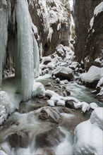 Wild river Partnach in the Partnachklamm with long icicles and snow in winter