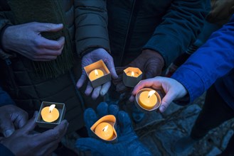 Hands holding devotional candles at dusk