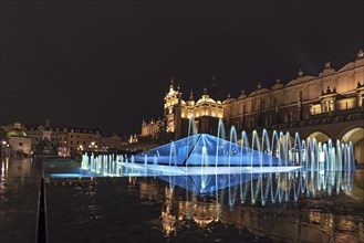 Illuminated fountain with cloth halls at night