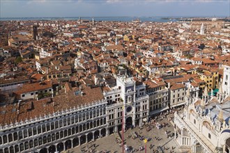 Procuratie Vecchie building with St Mark's clock tower and St Mark's Basilica and old architectural style residential buildings with terracotta rooftops taken from the Campanile bell tower in St Mark'...