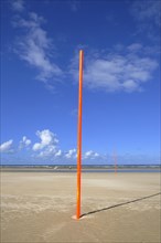 Orange-red marker posts on the beach