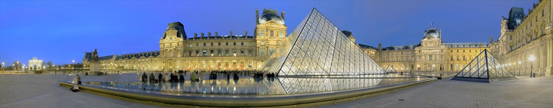 Illuminated Louvre with glass pyramid at dusk