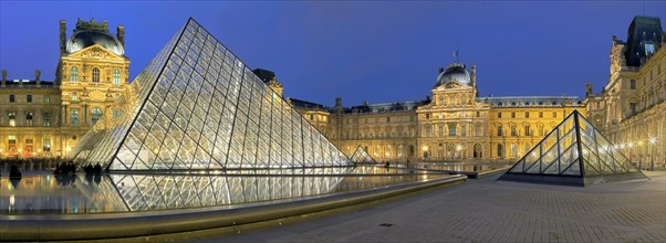 Illuminated Louvre with glass pyramid at dusk