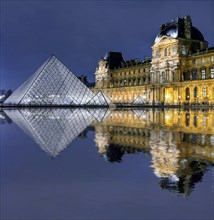 Illuminated Louvre with glass pyramid with reflection in the water