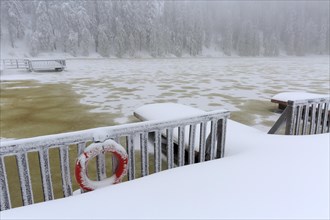 Jetty on frozen Mummelsee in winter with snow