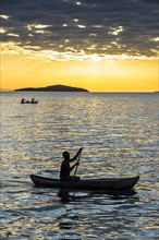 Man in a little fishing boat at sunset