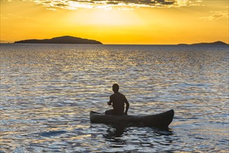 Man in a little fishing boat at sunset