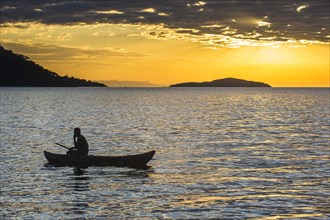 Man in a little fishing boat at sunset