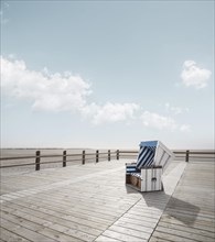 Single blue-white beach chair stands on beach chair plateau at the wide beach of Sankt Peter-Ording