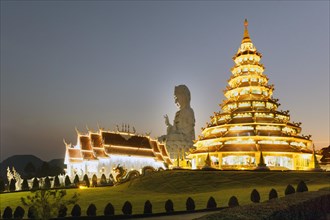 Nine-storey Chinese pagoda and chapel in front of the huge Guan Yin statue at dusk