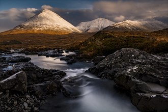 AltDearg Mor with snow-covered peaks of the Cullins Mountains in Highland landscape
