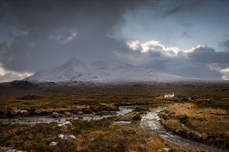 Waterfall of AltDearg Mor with snowy peaks of Marsco and Sgurr Nan Gillean and small house