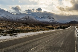 Snowy mountain tops of Ben Lee with clouds in Highland landscape and road cup in the foreground
