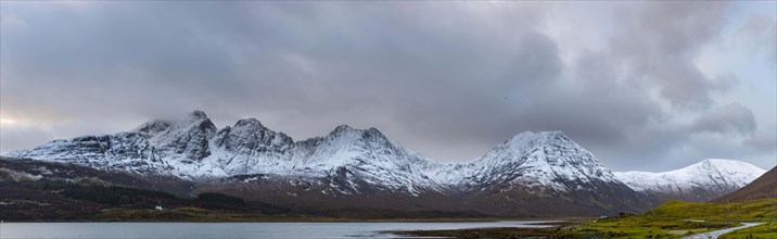 Loch Slapin with small house in Highland landscape with snowy Cullin mountains in the background