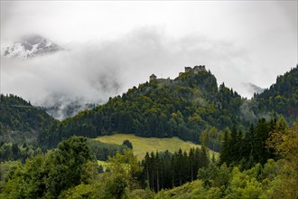Castle ruin Ehrenberg with deciduous forest and mountains in the fog