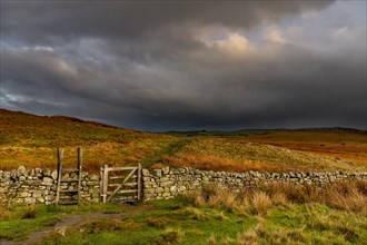 Stone wall in autumn landscape with dark sky