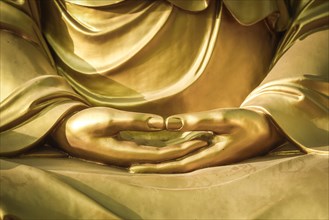 Hands of a Buddha sculpture in meditation posture